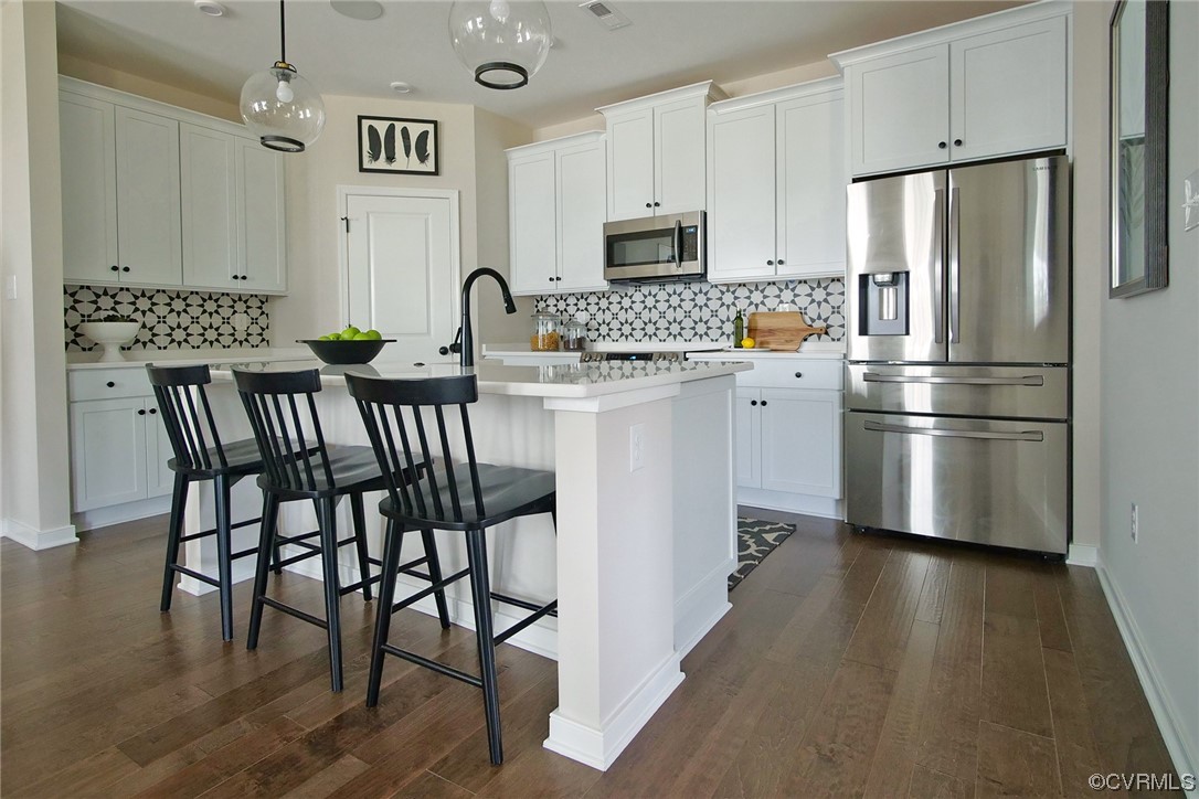 a kitchen with stainless steel appliances granite countertop a dining table chairs refrigerator and microwave