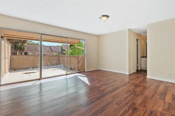 a view of empty room with wooden floor and fan