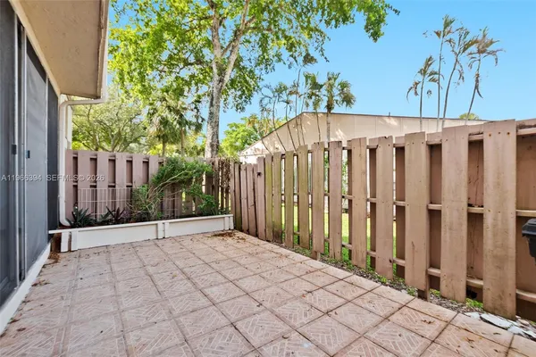 a view of a white house with a small yard and large trees
