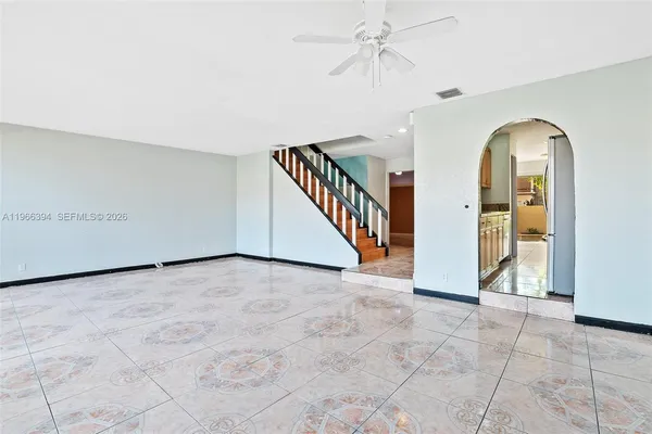 a view of an empty room with a chandelier fan and windows