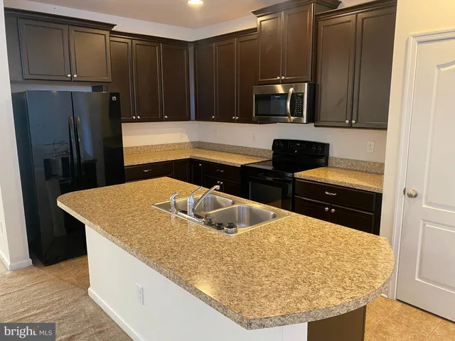 a kitchen with stainless steel appliances granite countertop a sink a microwave a refrigerator and wooden cabinets