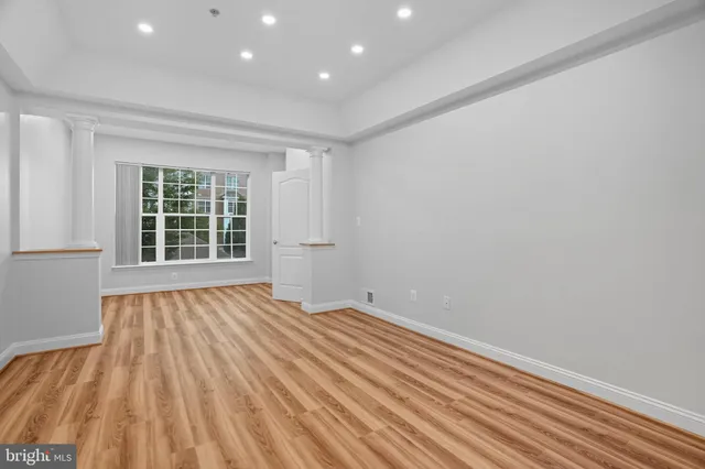 a view of an empty room with a window and wooden floor