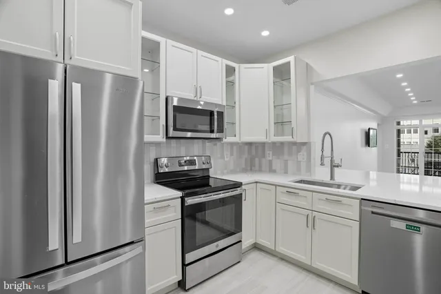 a kitchen with white cabinets sink and stainless steel appliances