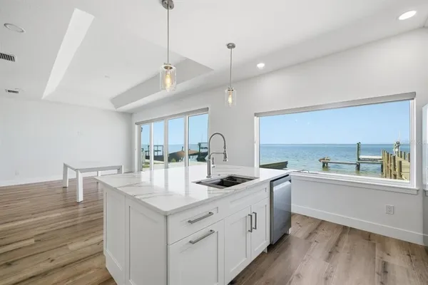 a kitchen with white cabinets appliances and wooden floor