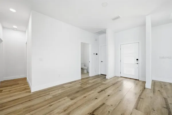 a large white kitchen with wooden floors and view living room