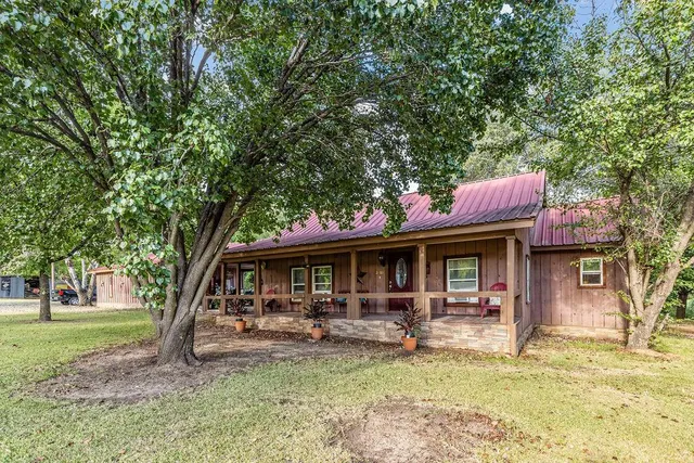 a front view of a house with garden and trees