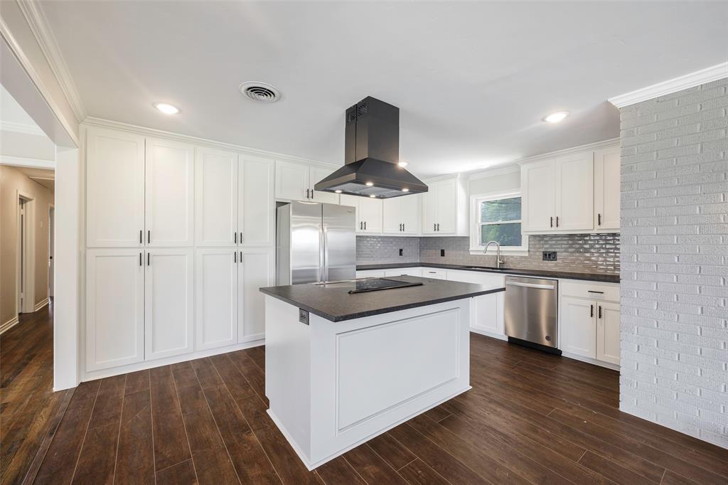 2323 Sutter Street Dallas, TX 75216 - Photo 8 of 30 Kitchen featuring a center island, crown molding, appliances with stainless steel finishes, island exhaust hood, and tasteful backsplash