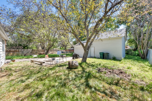 501 Canyon Road Ogden, UT 84404 - Photo 5 of 30 Expansive backyard featuring a detached garage with horizontal siding, mature deciduous trees, a concrete patio area, and perimeter fencing
