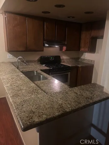 a kitchen with granite countertop a sink a stove and wooden cabinets