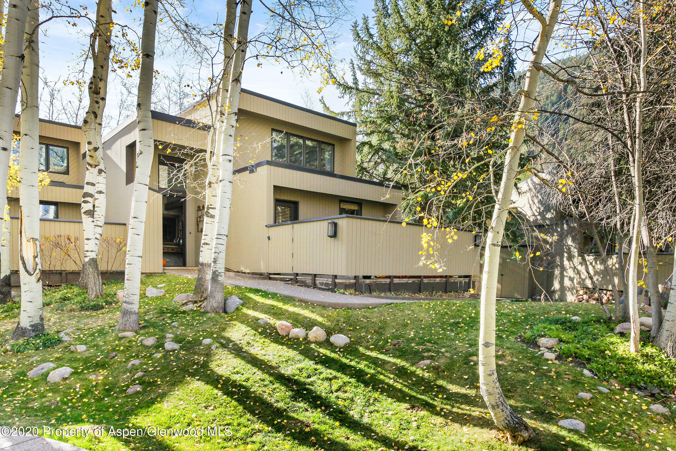 1439 Crystal Lake Road Aspen, CO 81611 - Photo 22 of 34 a view of a white house next to a yard with big trees