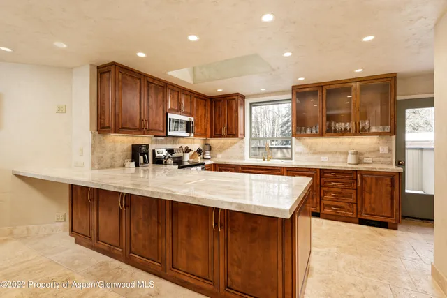 a kitchen with stainless steel appliances granite countertop wooden cabinets a stove top oven a sink and dishwasher