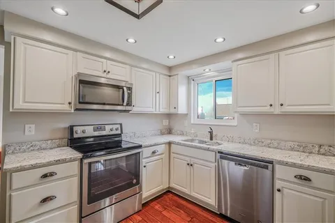 a kitchen with stainless steel appliances granite countertop a sink dishwasher a stove and a microwave oven with cabinets