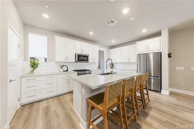a kitchen with stainless steel appliances kitchen island granite countertop a table chairs sink refrigerator and cabinets