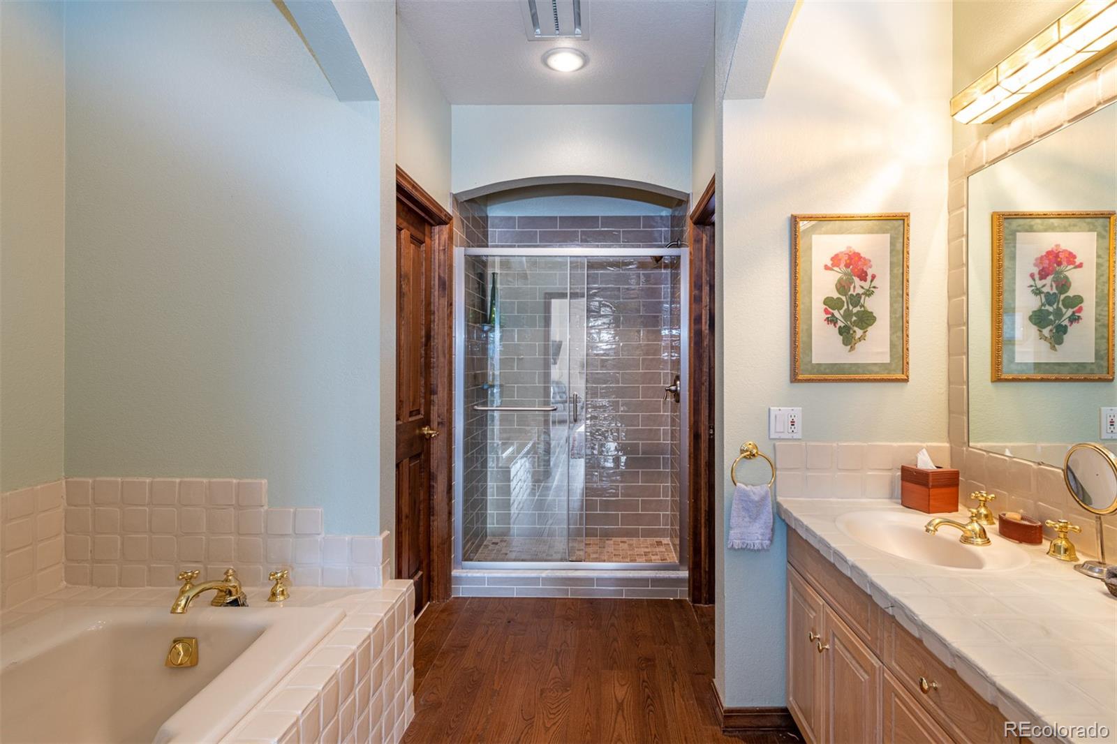 3942 South Pinehurst Circle Denver, CO 80235 - Photo 20 of 25 a bathroom with a tub a sink and mirrors