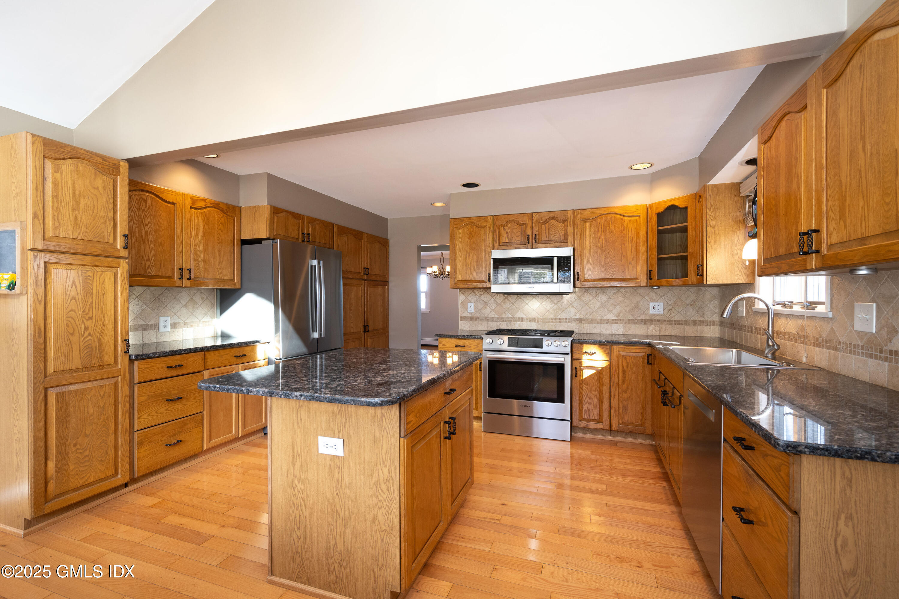 46 Cambridge Road Stamford, CT 06902 - Photo 9 of 29 a kitchen with stainless steel appliances granite countertop wooden cabinets a sink and dishwasher a stove top oven with wooden floor
