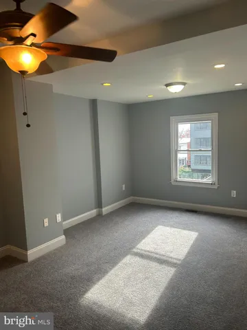 an empty room with a window and chandelier fan