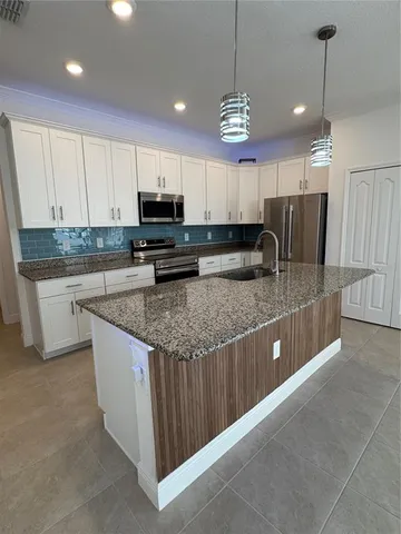 a kitchen with stainless steel appliances granite countertop a sink a stove a refrigerator a center island a stove and cabinets