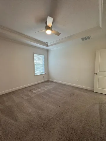 an empty room with a chandelier fan and windows