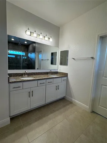 a spacious bathroom with a double vanity sink a mirror and a bathtub