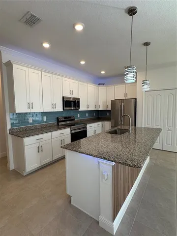 a kitchen with stainless steel appliances granite countertop a sink a stove a microwave a center island and cabinets