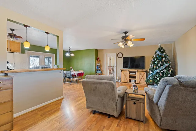 a living room with furniture a flat screen tv and a dining table with wooden floor