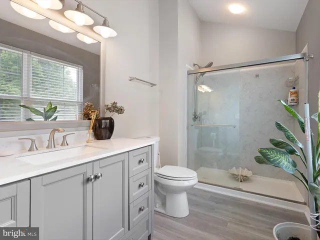 a bathroom with a sink a toilet a mirror and shower