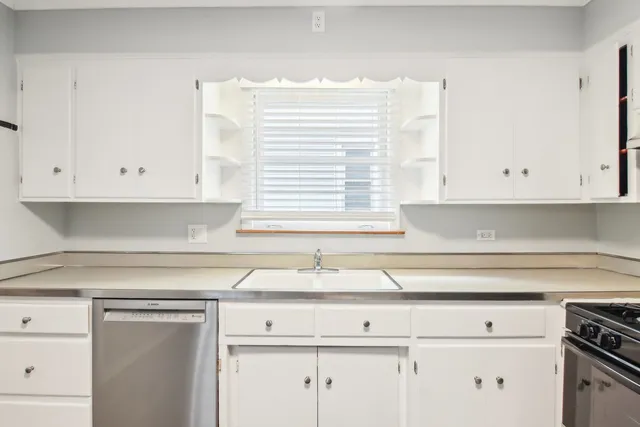 a kitchen with white cabinets and sink