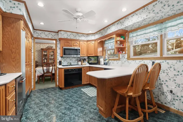 a open kitchen with stainless steel appliances granite countertop a stove a sink dishwasher a dining table and chairs with wooden floor