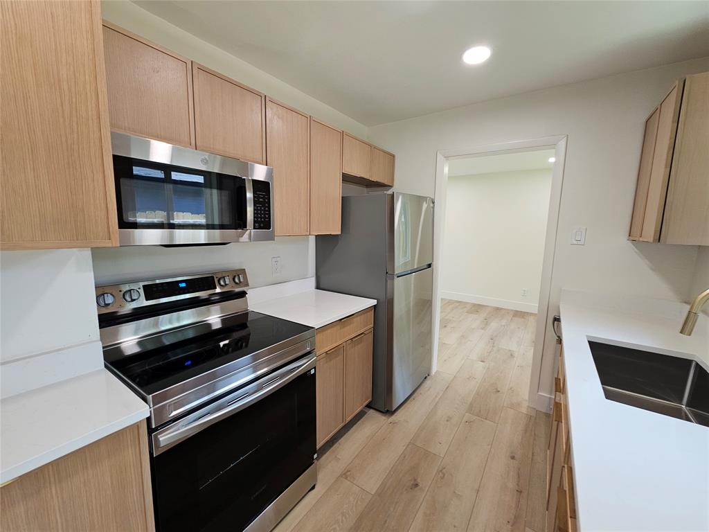 1725 R Avenue, Unit 1725 Plano, TX 75074 - Photo 8 of 20 Kitchen featuring wood-finish cabinetry, stainless steel appliances, white countertops, and light wood-finish flooring