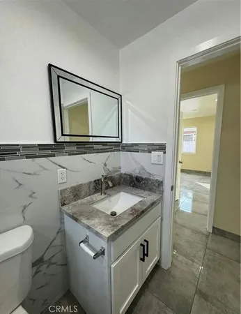 a bathroom with a granite countertop toilet sink and mirror