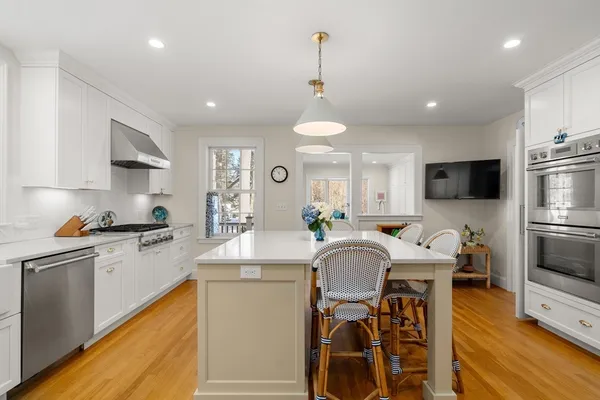 a kitchen with stainless steel appliances granite countertop a stove top oven a sink dishwasher a dining table and chairs with wooden floor