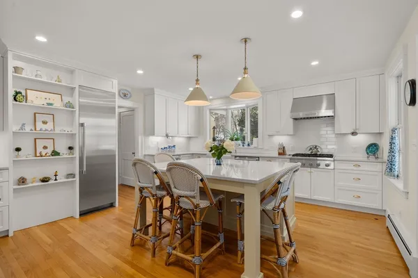 a kitchen with stainless steel appliances a dining table chairs stove refrigerator and cabinets