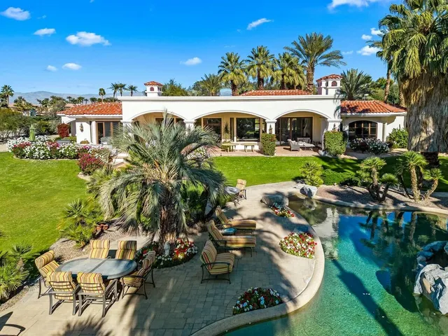 a view of a patio with table and chairs potted plants and large palm trees