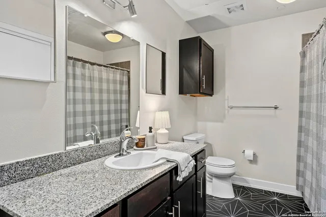 a bathroom with a granite countertop sink and a toilet