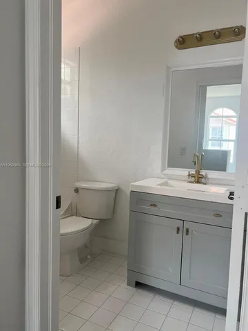 a bathroom with a granite countertop toilet sink and mirror
