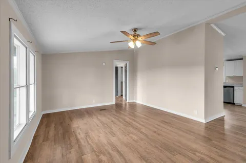 a view of an empty room with a window and wooden floor