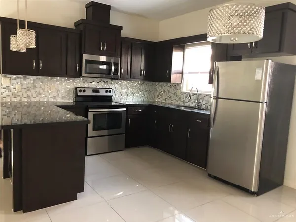 a kitchen with stainless steel appliances granite countertop a refrigerator a stove a sink and a microwave