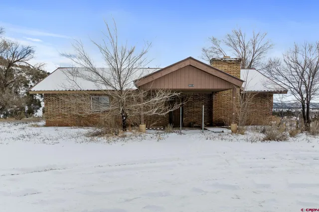 a front view of a house with a yard covered in snow