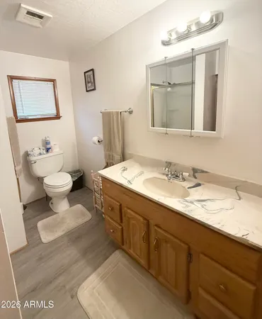 a bathroom with a granite countertop sink mirror and a toilet