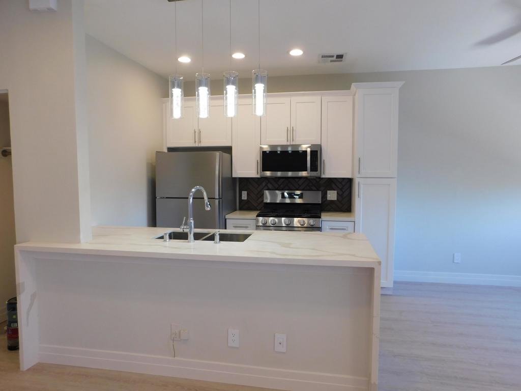a view of kitchen with refrigerator stove and a sink