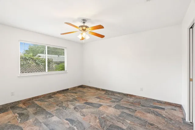 an empty room with a window and a fan