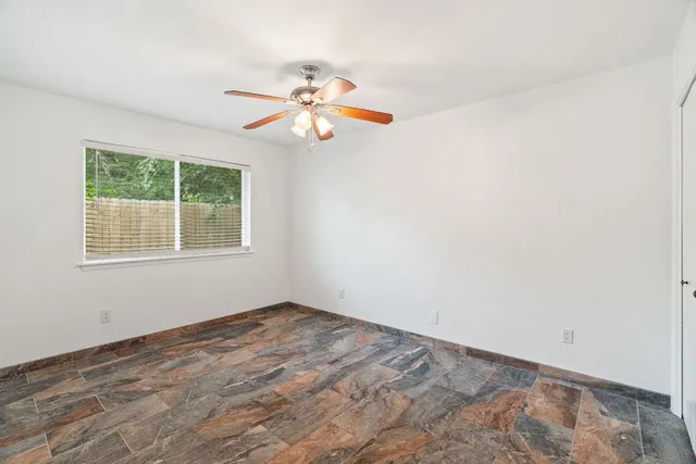 an empty room with windows and fan
