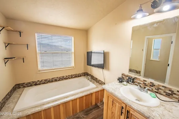 a bathroom with a granite countertop sink a mirror and a bathtub