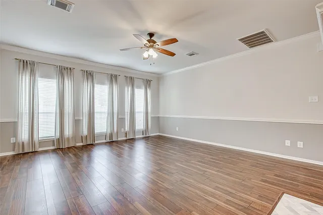 a view of empty room with wooden floor and fan