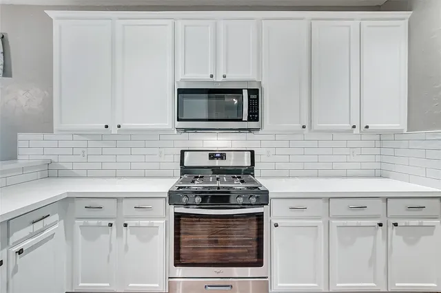 a kitchen with white cabinets a sink stove and refrigerator