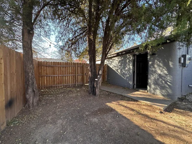 a view of a house with a large tree and wooden fence