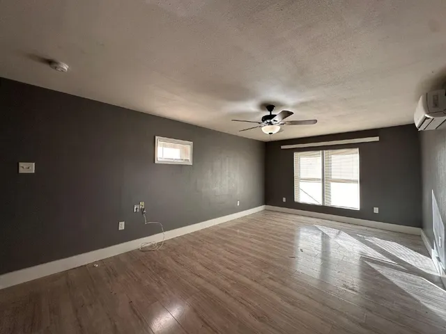 a view of an empty room with a window and wooden floor