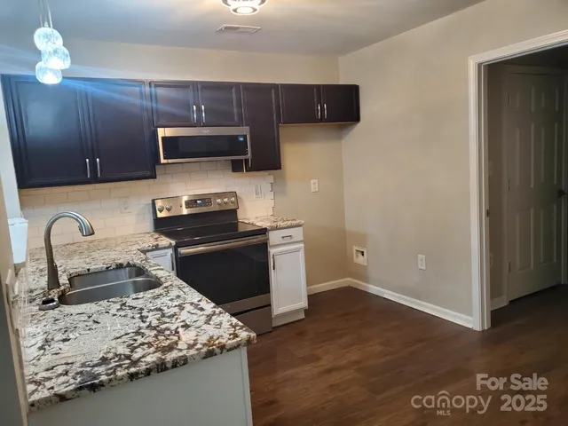 a kitchen with stainless steel appliances granite countertop a stove refrigerator and microwave