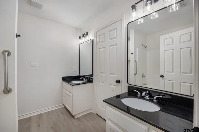 a bathroom with a granite countertop sink a mirror and a shower