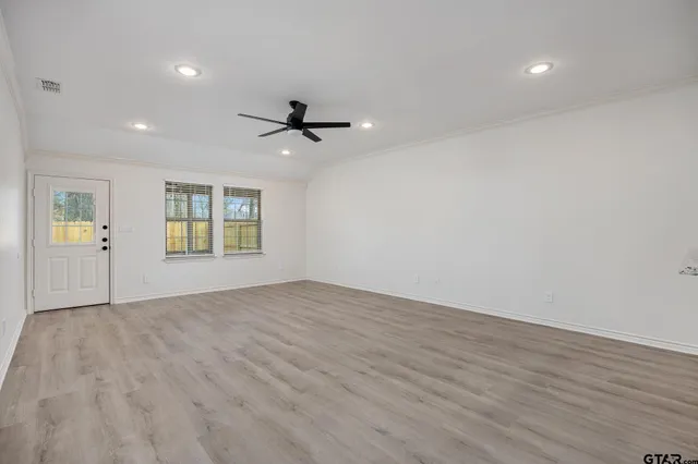 an empty room with windows and ceiling fan